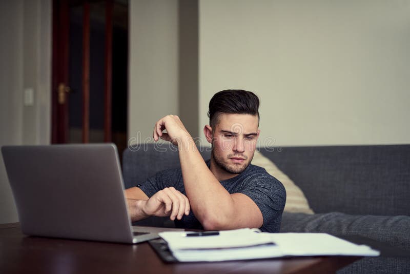 Time for a coffee break yet. a driven young man using his laptop to work from home. stock image
