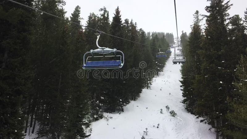Time lapse hyper lapse video clip of four person ski chair lift on a snowy mountain stock video footage