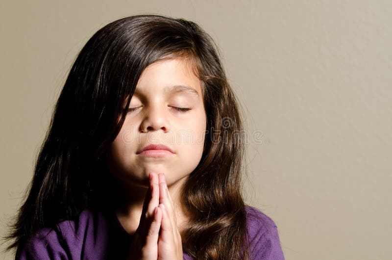 A little girl praying with her eyes closed. A little girl praying with her eyes closed.