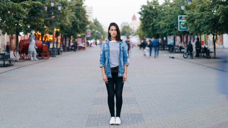 Time-schackningsperiod stående av den stressade unga kvinnan som bara står i bärande jeans för centrum och grov bomullstvillomsla
