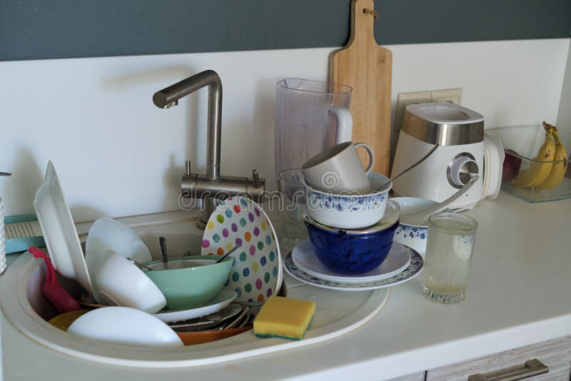 Time to clean: A daunting stack of soiled plates, bowls, and utensils fills the sink, accompanied by a sponge for