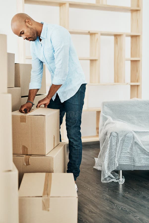 Time To Get All Settled in. a Young Man Unpacking Boxes while Moving