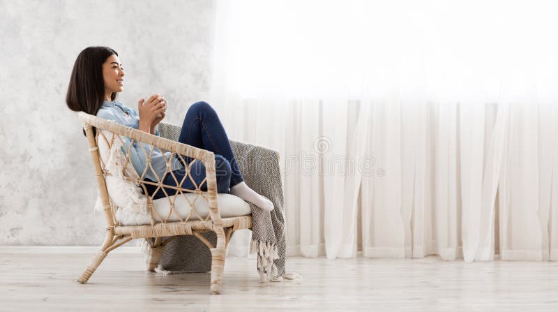 Time To Relax Asian Girl Enjoying Coffee In Wicker Chair At Home Stock