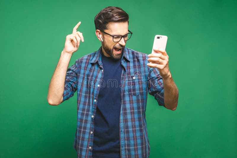 Time to relax. Handsome young man in headphones keeping eyes closed while dancing. Over green background. Isolated