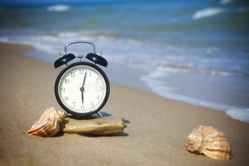 Tempo di relax! Il mare è chiamare! L'allarme e conchiglie sulla riva del mare caldo.