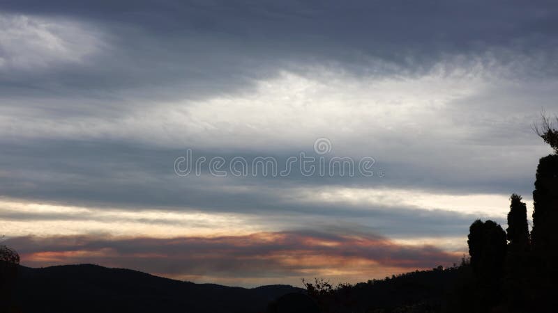 Timelapse with clouds and smoke from controlled fuel reduction burns passing by on top of Tasmanian landscape with eucalyptus