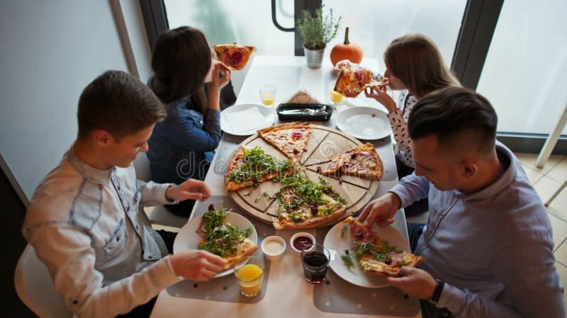 Timelapse di giovani amici che mangiano una pizza alla pizzeria, alla conversazione ed alla risata