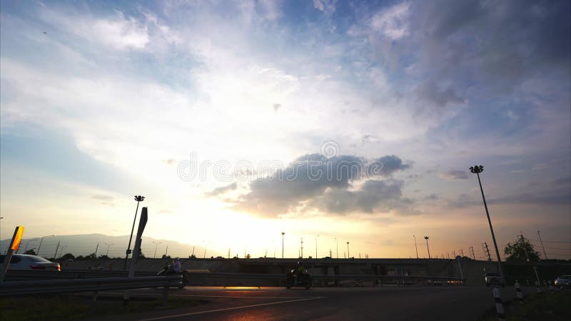 Timelapse nubes de flujo rápido puesta de sol en el cielo de la noche con coches conduciendo en el puente.