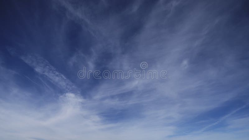 Timelapse of scattered soft clouds moving in blue sky, and it's getting darker when the nightfall stock video footage