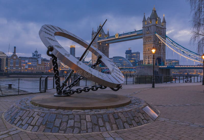 The Timepiece Sundial and Tower Bridge on Thames river in London, United Kingdom at sunset on a cloudy day