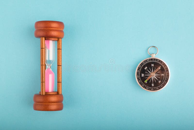 Timglas och kompass p? bl? bakgrund f?r riktning eller spring ut ur tidbegrepp arkivbild Timglas och kompass p? bl? bakgrund f?r riktning eller spring ut ur tidbegrepp arkivbild