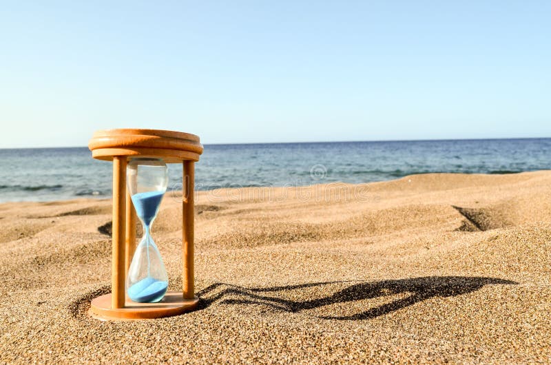 Timglasklocka på sandstranden arkivbild
