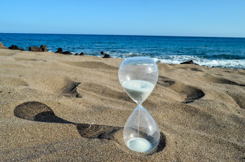 Timglasklocka på sandstranden royaltyfri foto