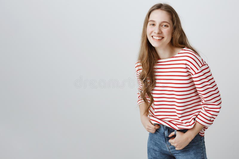 Timid and kind girl trying make new friends. Studio shot of positive attractive female student holding hands on jeans