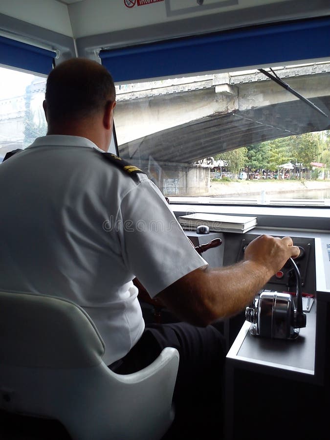 Timisoara / Romania - 13 ottobre 2019: il capitano della nave siede su una sedia bianca e controlla la nave Passaggi per imbarcaz fotografia stock