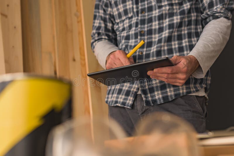 Timmerman die digitale tablet in kleine bedrijfshoutbewerkingsworkshop gebruiken stock foto Timmerman die digitale tablet in kleine bedrijfshoutbewerkingsworkshop gebruiken stock foto
