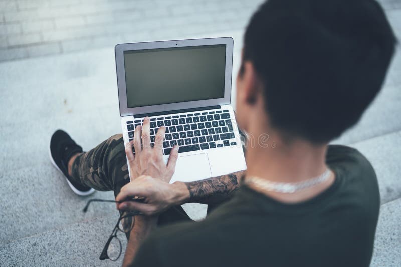 Tinere adolescente care tastează pe laptop și stau pe scări în clădirea de pe strada orașului stock image