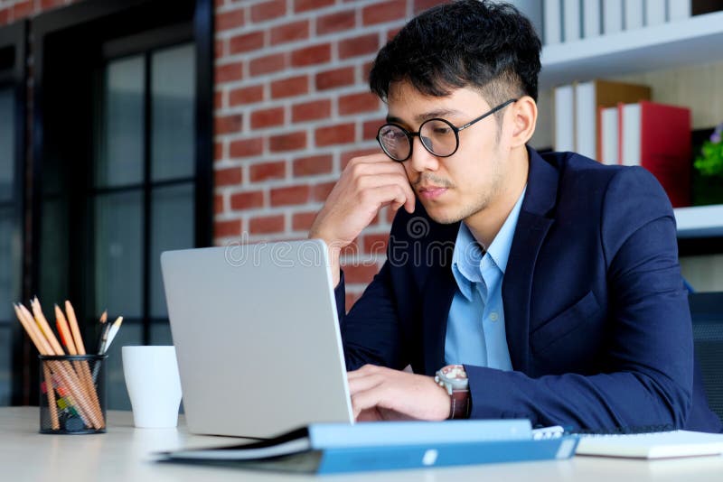 Tinere birouri asiatice se luptă cu un computer de tip notebook frustrat de om de afaceri asiatic care se uită la calculator în ti royalty free stock photo