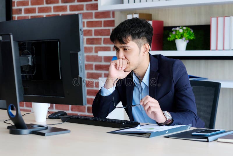 Tinere birouri asiatice se luptă cu un om de afaceri asiatic frustrat de calculator care se uită la calculator în timp ce lucrează royalty free stock photo
