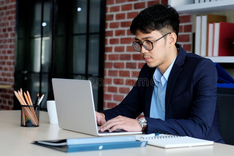 Tinere birouri asiatice se luptă cu un om de afaceri asiatic frustrat de calculator care se uită la calculator în timp ce lucrează royalty free stock images