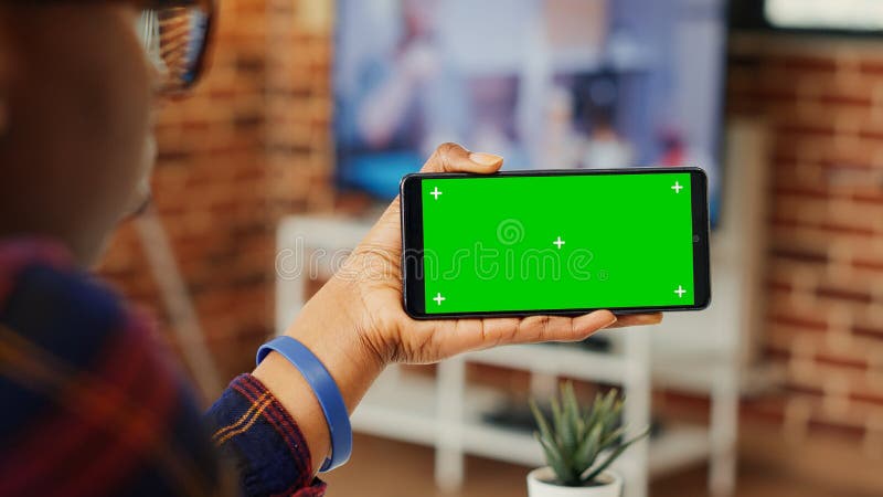 Tineri adulți care se uită la ecranul verde orizontal pe telefon stock photography