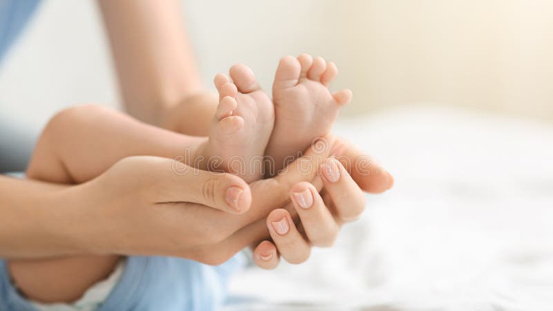 Tiny feet of a newborn baby in caring mother`s hands