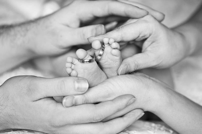 Tiny feet of newborn baby with wedding rings on it