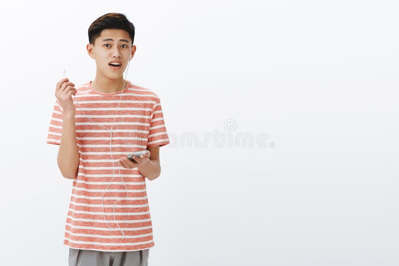 Tipo che è distratto mentre musica d'ascolto in cuffie che decollano un earbud e che esaminano interrogate la macchina fotografic immagini stock libere da diritti