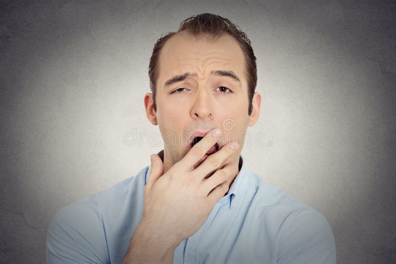 Closeup portrait headshot sleepy young businessman funny guy placing hand on mouth yawning looking at camera isolated grey wall background. Negative human emotion face expression feeling body language. Closeup portrait headshot sleepy young businessman funny guy placing hand on mouth yawning looking at camera isolated grey wall background. Negative human emotion face expression feeling body language