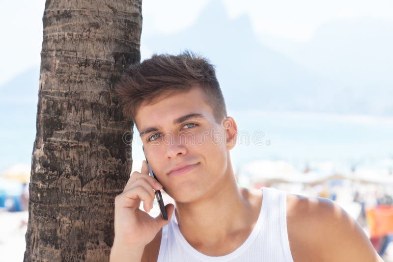 Tipo fresco che ascolta al telefono alla spiaggia di Ipanema a Rio de Janeiro fotografie stock libere da diritti Tipo fresco che ascolta al telefono alla spiaggia di Ipanema a Rio de Janeiro fotografie stock libere da diritti