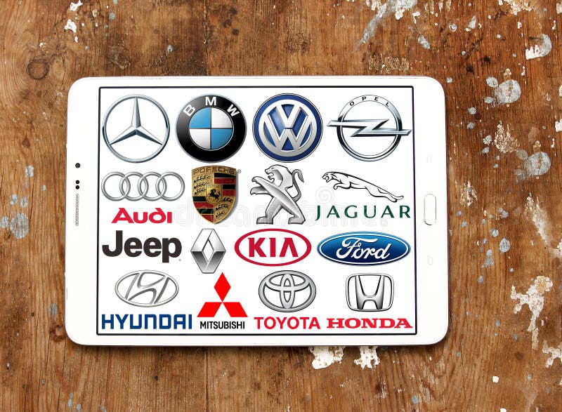 Collection of the famous car brands logos on white tablet on wooden background. Brands like mercedes , volkswagen , bmw , toyota , ford , audi , jeep , jaguar , kia , fiat , opel , hyundai. Collection of the famous car brands logos on white tablet on wooden background. Brands like mercedes , volkswagen , bmw , toyota , ford , audi , jeep , jaguar , kia , fiat , opel , hyundai