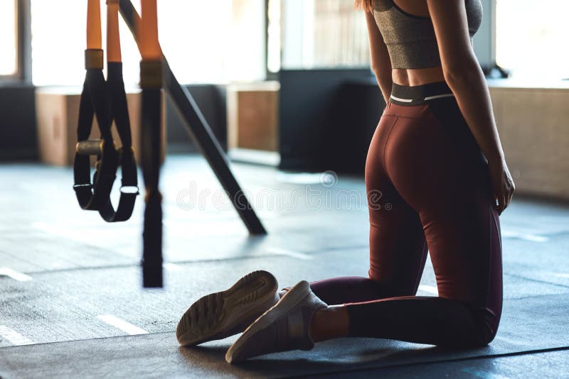 Tir cultivé de la femme sportive dans les vêtements de sport s'exerçant sur le sol du gymnase, se mettre à genoux image libre de droits