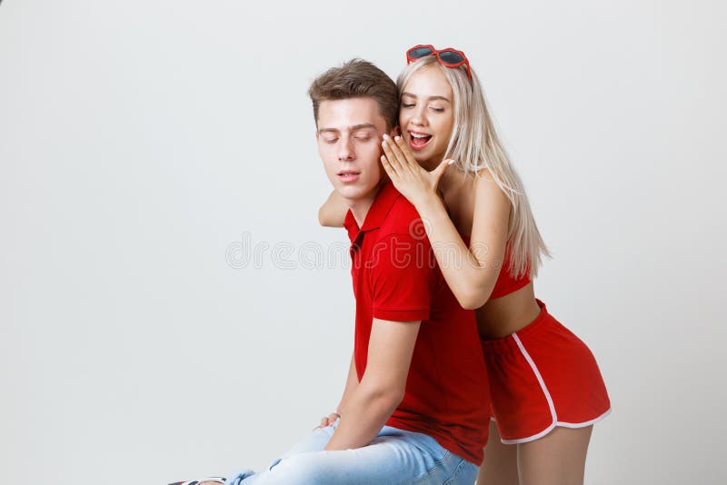 Tir de studio de jeune femme chuchotant quelque chose à son ami Les jeunes amants partagent des secrets photo stock Tir de studio de jeune femme chuchotant quelque chose à son ami Les jeunes amants partagent des secrets photo stock