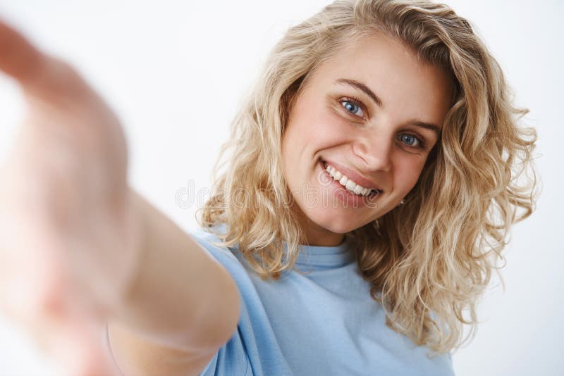 Tir en gros plan de femme attirante heureuse amicale et sociable avec des yeux bleus et le sourire sincère atteignant la caméra a photos stock Tir en gros plan de femme attirante heureuse amicale et sociable avec des yeux bleus et le sourire sincère atteignant la caméra a photos stock