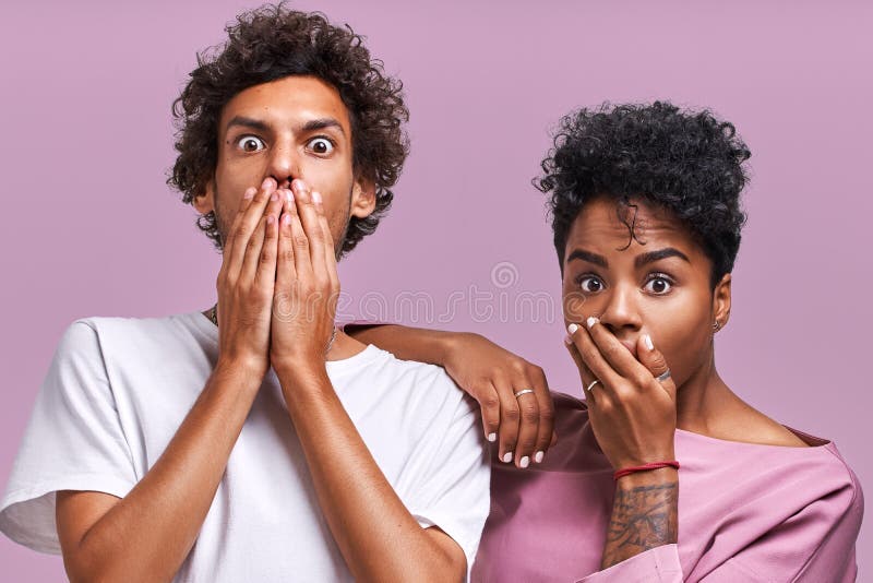 Tir horizontal regard femelle d'Afro-américain de jeune et masculin choqué avec des expressions effrayées effrayées à l'appareil- photos stock Tir horizontal regard femelle d'Afro-américain de jeune et masculin choqué avec des expressions effrayées effrayées à l'appareil- photos stock