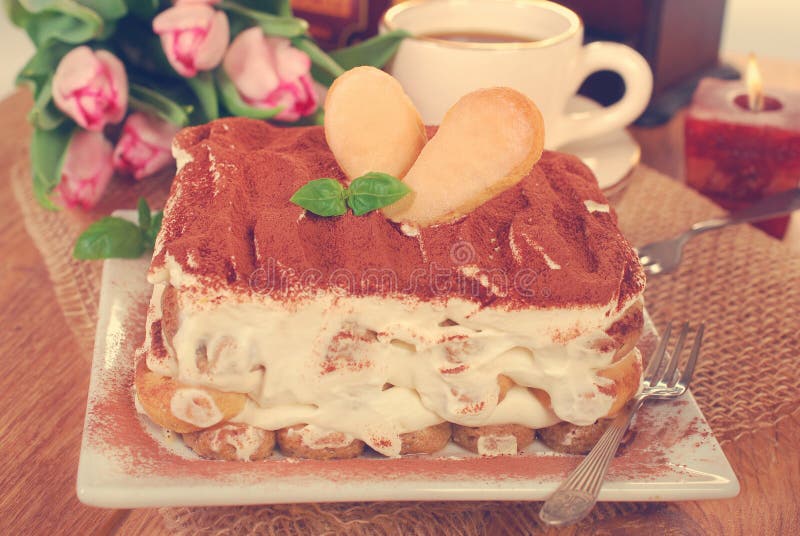 Tiramisu cake. Homemade tiramisu cake ,cup of coffee and pink tulips on the table royalty free stock images Tiramisu cake. Homemade tiramisu cake ,cup of coffee and pink tulips on the table royalty free stock images