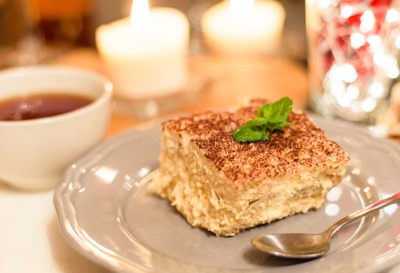 Tiramisu durch Kerzenlicht, romantisches Datum in Italien, Tiramisunachtisch auf einer Porzellanplatte stockfotografie