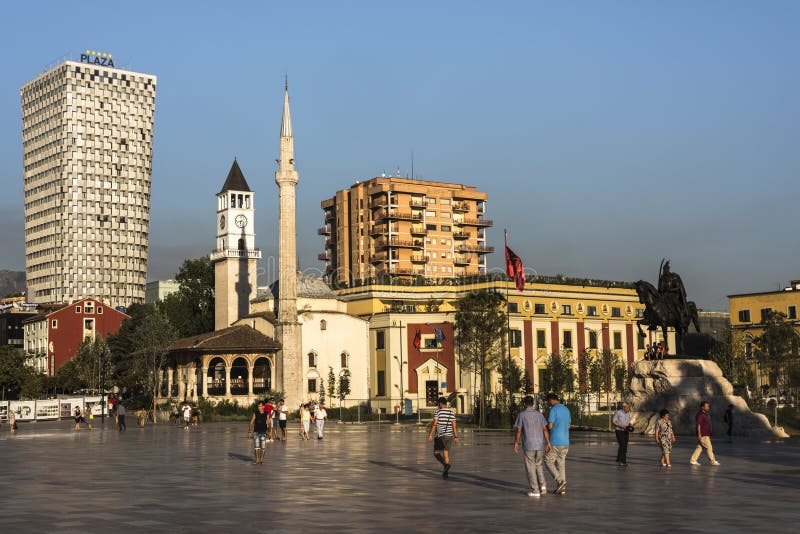 TIRANA, ALBANIË - AUGUSTUS 1, 2017: Plaatselijke bewoners bij Skanderbeg-Vierkant in de vroege avond voor het Pleinhotel, Et ‚boo stock afbeelding TIRANA, ALBANIË - AUGUSTUS 1, 2017: Plaatselijke bewoners bij Skanderbeg-Vierkant in de vroege avond voor het Pleinhotel, Et ‚boo stock afbeelding
