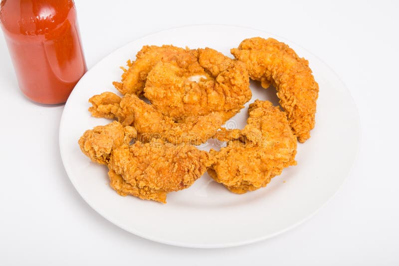 Hot, crispy chicken strips on a white plate with hot sauce. Hot, crispy chicken strips on a white plate with hot sauce