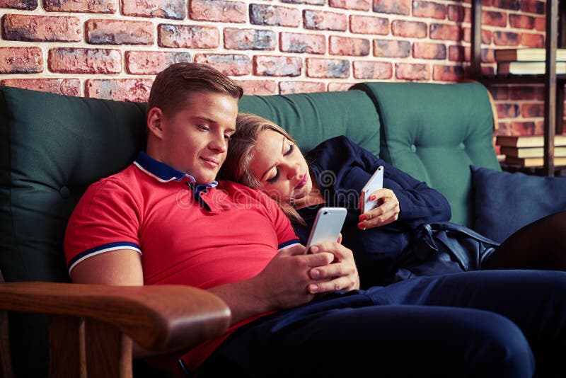 Tired Couple Relaxing On Sofa And Using Mobile Phone At Home Stock