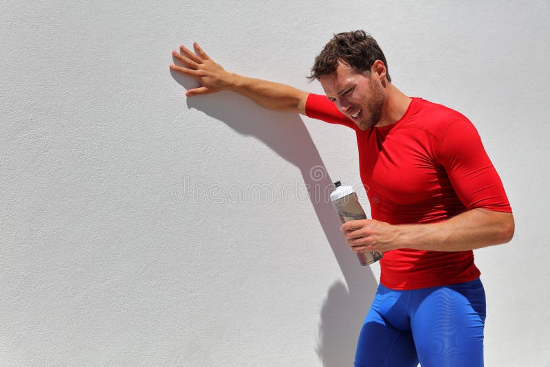 Tired exhausted dehydrated man runner drinking water bottle after workout. Running person taking a break after run. Fitness stock photography