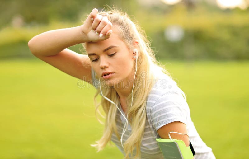Tired female runner in the park taking a break - Sporty woman breathing and resting after outdoor sport activity royalty free stock image Tired female runner in the park taking a break - Sporty woman breathing and resting after outdoor sport activity royalty free stock image