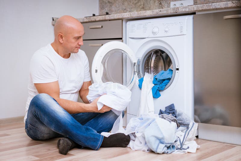 Tired Man Sits with Laundry at the Washing Machine Stock Photo - Image ...