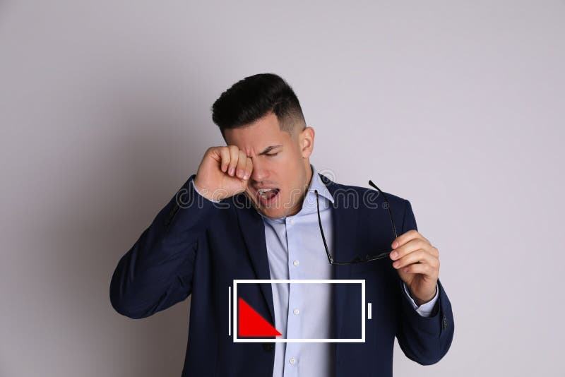 Tired man yawning and illustration of discharged battery on light grey background royalty free stock photography
