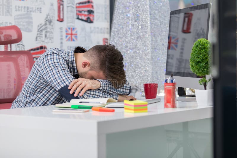 Tired overworked businessman sleeping over a laptop in a desk at job in his office. Tired overworked businessman sleeping over a laptop in a desk at job in his office.