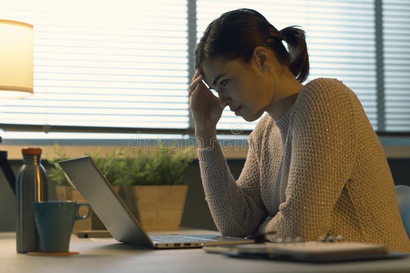 Tired woman with headache working with a laptop stock photography