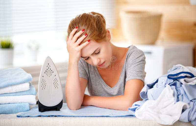 Tired woman housewife ironing clothes iron in laundry