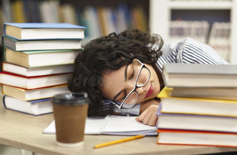 Tired woman napping on books stack in library