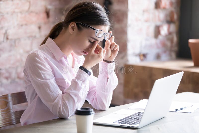 Tired businesswoman holding eyeglasses and massaging nose bridge royalty free stock photos
