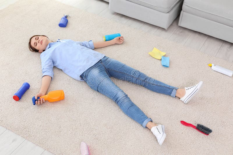 Tired young woman lying on carpet surrounded by cleaning supplies royalty free stock photography Tired young woman lying on carpet surrounded by cleaning supplies royalty free stock photography